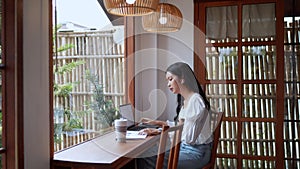 Entrepreneur working at a nearby cafe conversing with colleagues using earphones