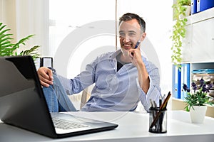 Entrepreneurial adult man sitting comfortably proudly at his desk