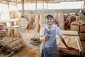 entrepreneurial man gives thumbs up in a woodworking workshop