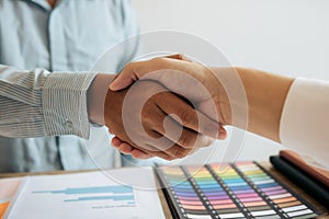 Entrepreneurs collaboration deal shaking hands in a modern office and financial paper graph on desk