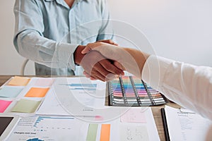 Entrepreneurs collaboration deal shaking hands in a modern office and financial paper graph on desk