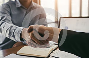 Entrepreneurs collaboration deal shaking hands in a modern office and financial paper graph on desk