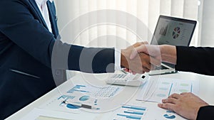 Entrepreneurs collaboration deal shaking hands in a modern office and financial paper graph on desk