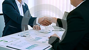 Entrepreneurs collaboration deal shaking hands in a modern office and financial paper graph on desk