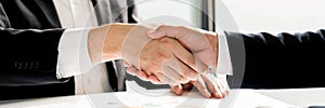 Entrepreneurs collaboration deal shaking hands in a modern office and financial paper graph on desk