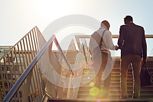 Entrepreneurs on the move. Rearview shot of unrecognizable businessmen walking up stairs outside.