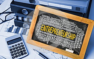 Entrepreneurship with related word cloud handwritten on blackboard