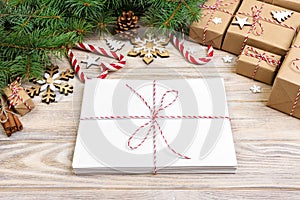 Envelope with blank sheet of paper on Christmas background - fir branch, pine cones, red ribbon, star and heart of sweets. Space f