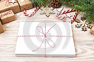 Envelope with blank sheet of paper on Christmas background - fir branch, pine cones, red ribbon, star and heart of