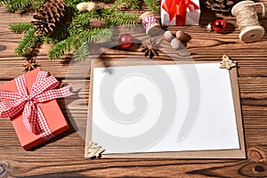 An envelope and a blank sheet of paper on a wooden tole with Christmas decorations.