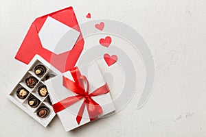 Envelope on colored background for Valentine Day with gift box and chocolate. Heart shaped with gift box of chocolates