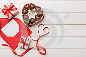 Envelope on colored background for Valentine Day with gift box and chocolate. Heart shaped with gift box of chocolates