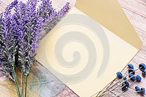 Envelope diagonally and lavender flowers on a light wooden background