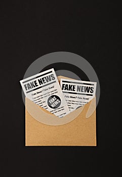 Envelope with FAKE NEWS newspapers over black