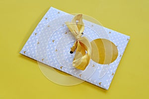 An envelope for a giftcard tied with a yellow ribbon and an empty round label