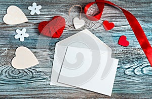Envelope, hearts and ribbon on a gray-blue wooden background.