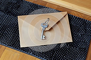 envelope with a key on top on a black doormat