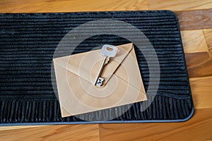 envelope with a key on top on a black doormat