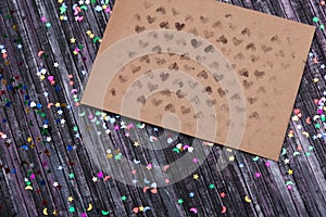 Envelope of Kraft paper. Love letter envelope. Wooden background. Social network. Sequins scattered on the background.