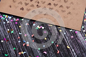 Envelope of Kraft paper. Love letter envelope. Wooden background. Social network. Sequins scattered on the background.