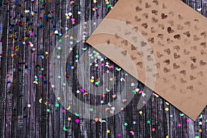 Envelope of Kraft paper. Love letter envelope. Wooden background. Social network. Sequins scattered on the background.