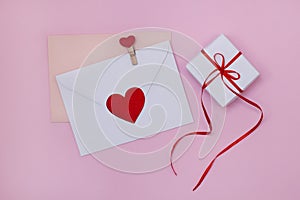 Envelope letter for valentine`s day. Composition with red hearts and gift box for Valentine`s Day on a pink background.