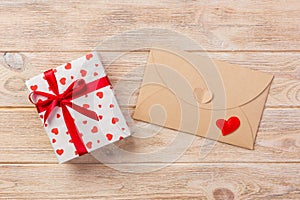 Envelope Mail with Red Heart and gift box over Orange Wooden Background. Valentine Day Card, Love or Wedding Greeting Concept