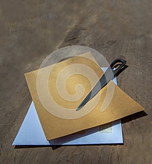 Envelope opener knife made of Stainless steel and two letter envelope on old wooden desk