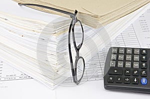 Envelope on overload old paperwork with vertical spectacles and calculator