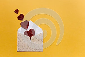 Envelope with symbols in the form of red hearts on a yellow background. Celebration.