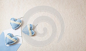 Envelope with three textile hearts spilling out on a stone background.