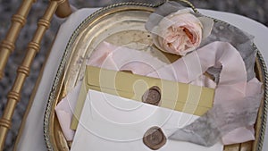 Envelopes with wax seals, delicate cream rose and ribbon on a beautiful vintage tray