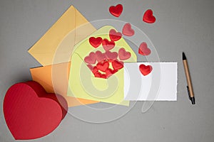 Envelopes and a white card for text with red hearts on a gray concrete background. Happy Valentine's Day greeting