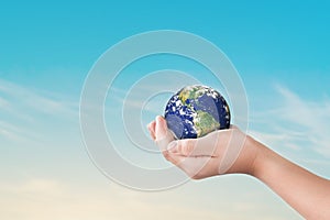 Environment day concept, Globe in child hands over blue sky background