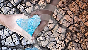 Environment Day.People hold hands in heart shape, with water and dry soil on the background. Water conservation concept