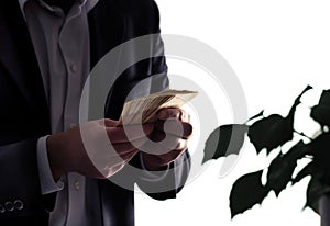 Environment or eco business and finance. Invest to sustainable and green energy. Man in a suit counting money. Plant with leafs.