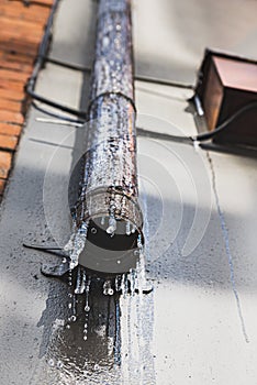 Environment and industrial style: water dripping down a rusty drainage pipe with icicles due to freezing condition. Dublin Ireland