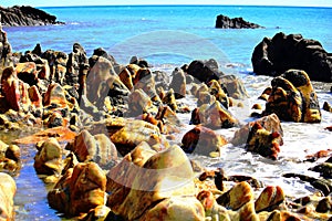 Environment, Marine landscape with unusual, polished and multi-colored stones on the beach, blue sea and white waves on the beach,