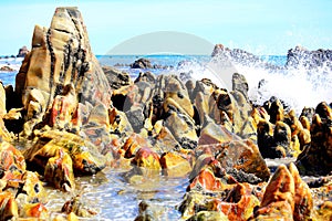 Environment, Marine landscape with unusual, polished and multi-colored stones on the beach, blue sea and white waves on the beach,