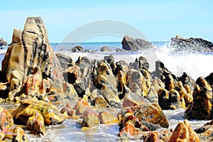 Environment, Marine landscape with unusual, polished and multi-colored stones on the beach, blue sea and white waves on the beach,