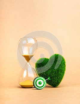 Environment sustainability, time and responsibility concept. Target of restoring our earth. 3d green target icon near hourglass