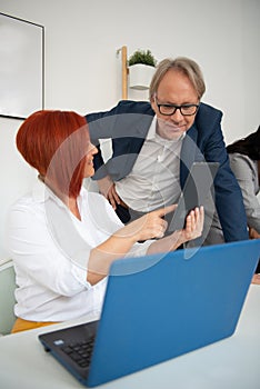 Environment of workers in their workplace consulting their computers and balance sheets