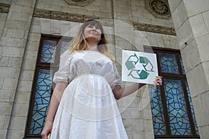 Environmental activist woman holding white board with recycle logo. Waste recycling