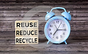 Environmental awareness and education concept. REUSE, REDUCE and RECYCLE written on wooden blocks with clock