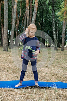 Environmental education for kids. Little girl holding young plant in hands against green tree background. Environment