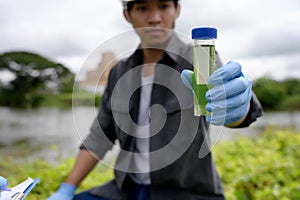 Environmental Engineers Inspect Water Quality, pH Test and Take Water sample notes in The Field Near Farmland, Fish Pond, Natural