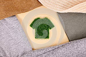 Environmental friendly clothing concept with shirt made out of grass surrounded by sweaters