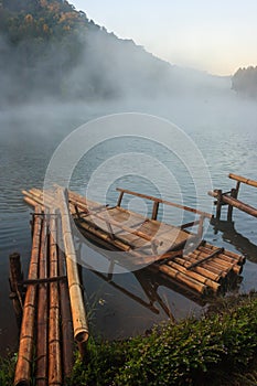 Environmental Friendly Outdoor Activity, Floating Bamboo Rafting in the morning in serene lake with sunlight and misty water