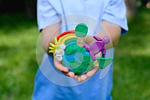 Environmental information and understanding. Child hands holding earth model with clay rainbow
