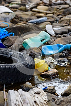 Environmental pollution. Rubber tire with plastic bottles and waste in dirty water